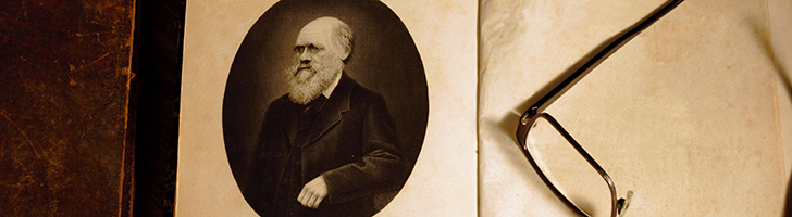 image of a book open to an image of Charles Darwin with eyeglasses next to it