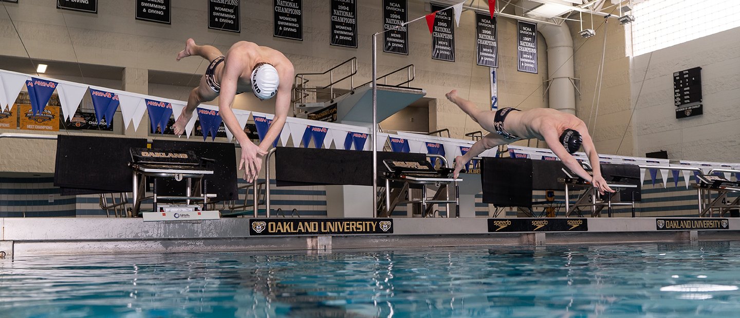 Two men diving into the swimming pool at Oakland University's aquatic center.