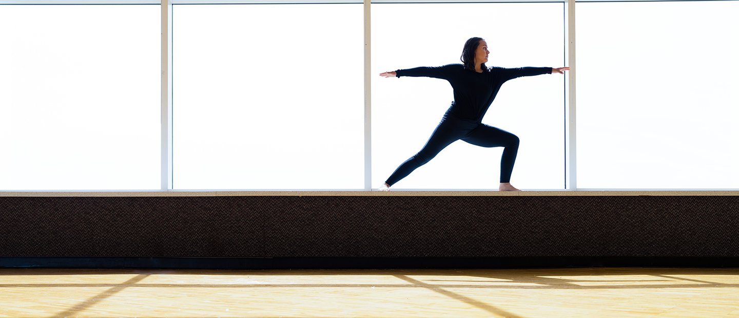A person performing a yoga pose on the ledge of a window.