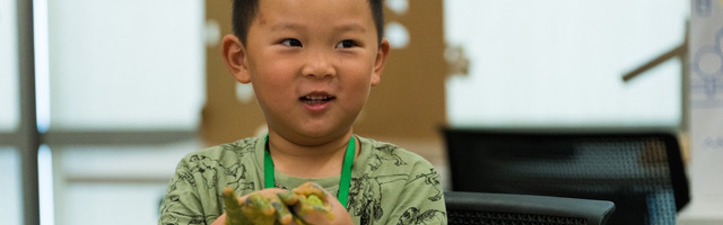 A graphic with a child who has something green all over his hands and is smiling
