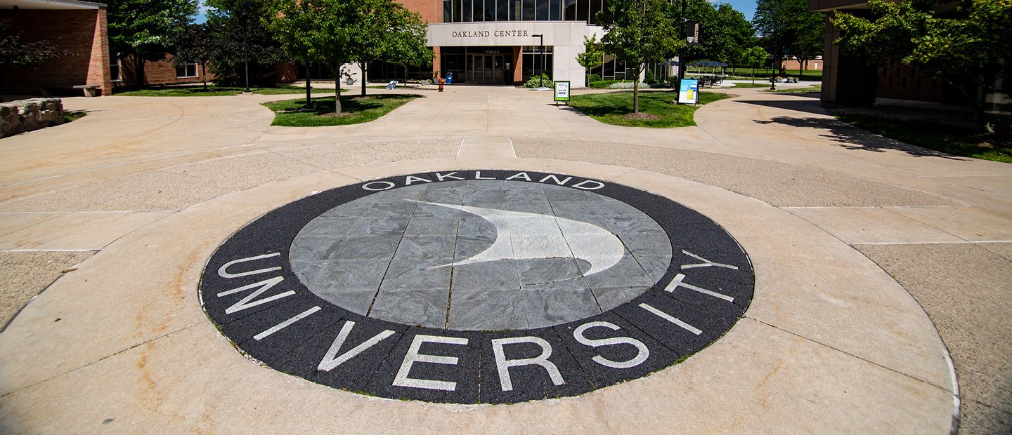 A black and grey Oakland University sail embedded in cement outside.
