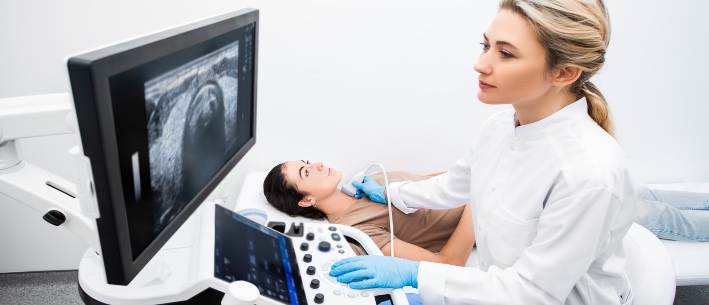 A sonographer imaging a woman's throat.