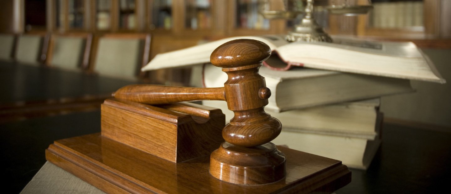 A judge's gavel resting on a wooden stand.