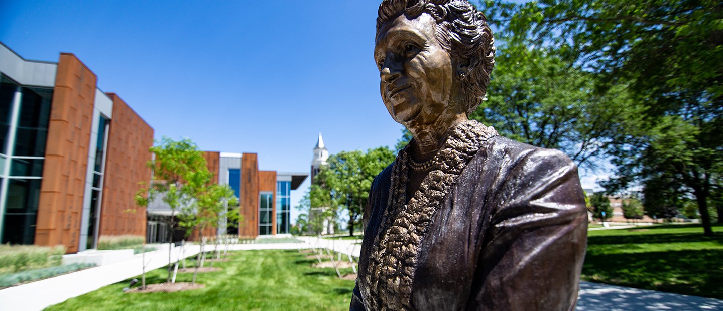A bronze statue of a woman outside of a building on Oakland University's campus.