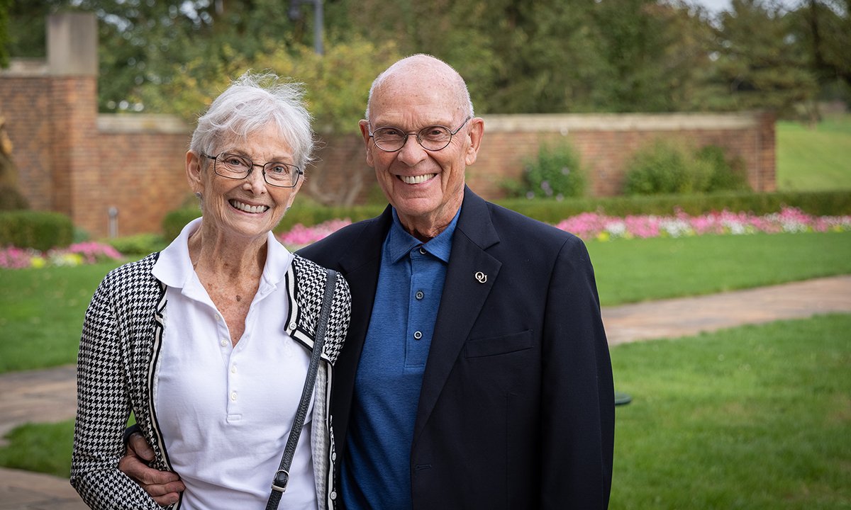 Barbara and Roger Calam, Ph.D. stand smiling in a garden next to each other.