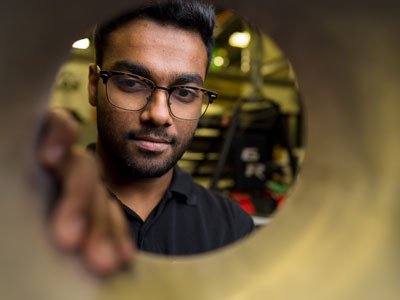 Man with glasses looking into a tube with the camera looking through the other way.