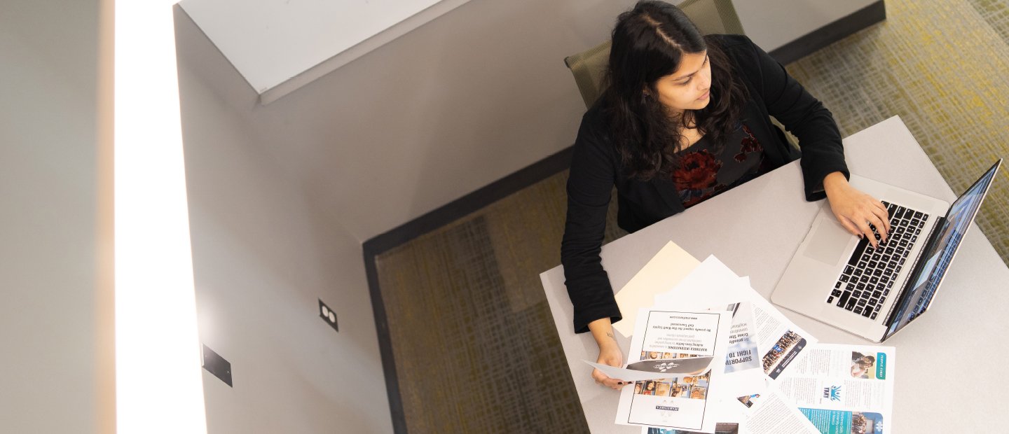 Person using a computer while analyzing papers