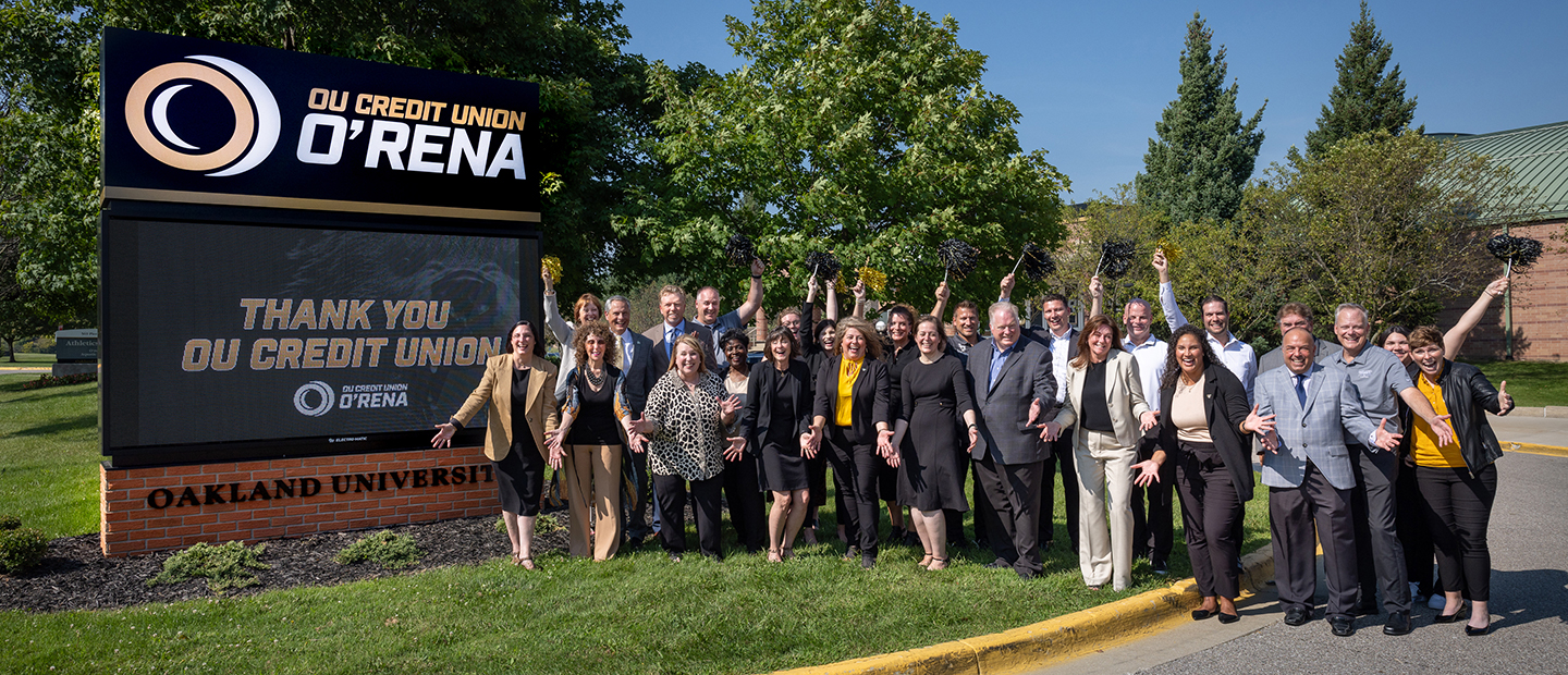 A large group of people posing near the OU Credit Union O'Rena marquee sign