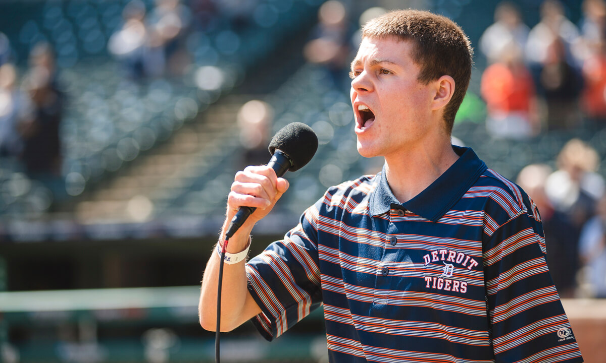 Young man singing into a microphone at comerica park