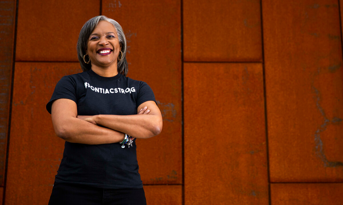 Woman standing in front of a metal wall with her arms crossed