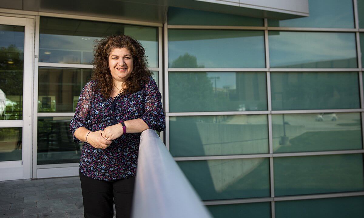 A woman stands outside a building smiling.