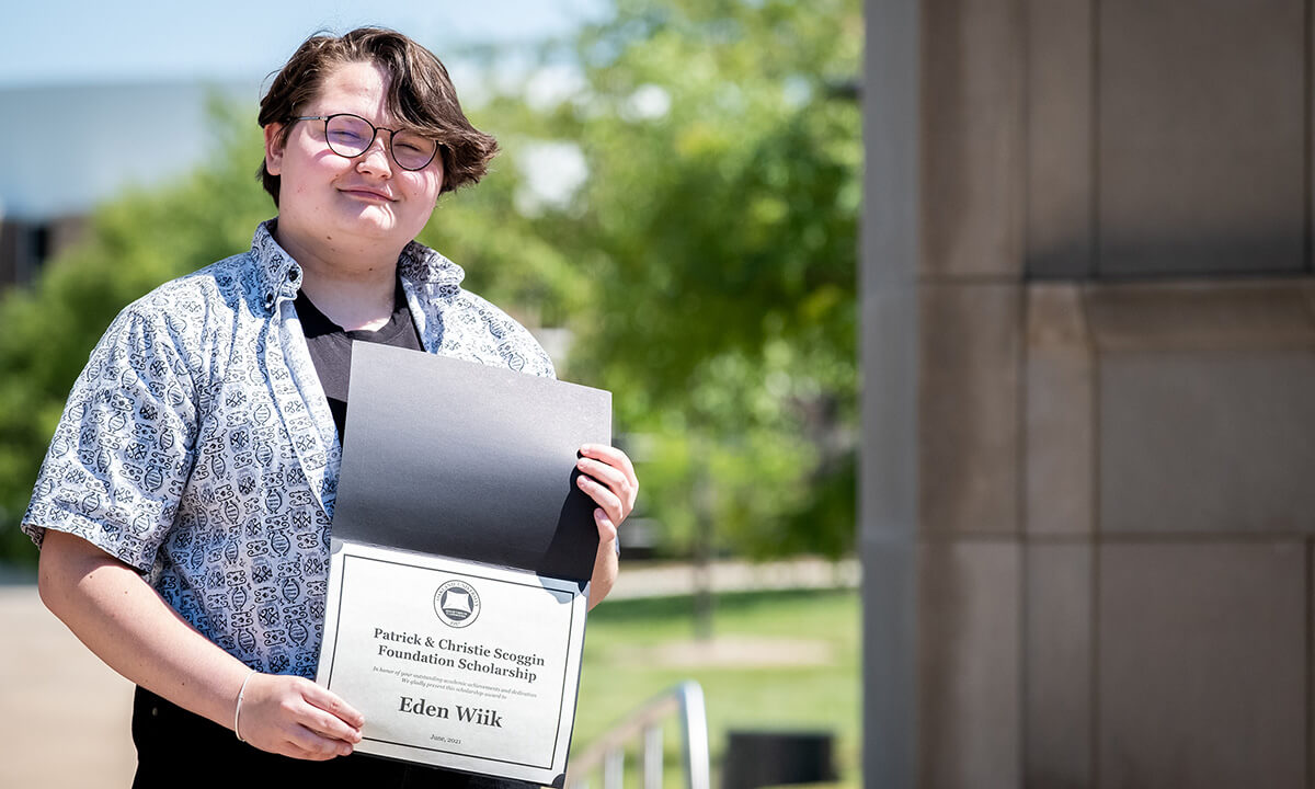 Eden Wiik holds up a scholarship award certificate.