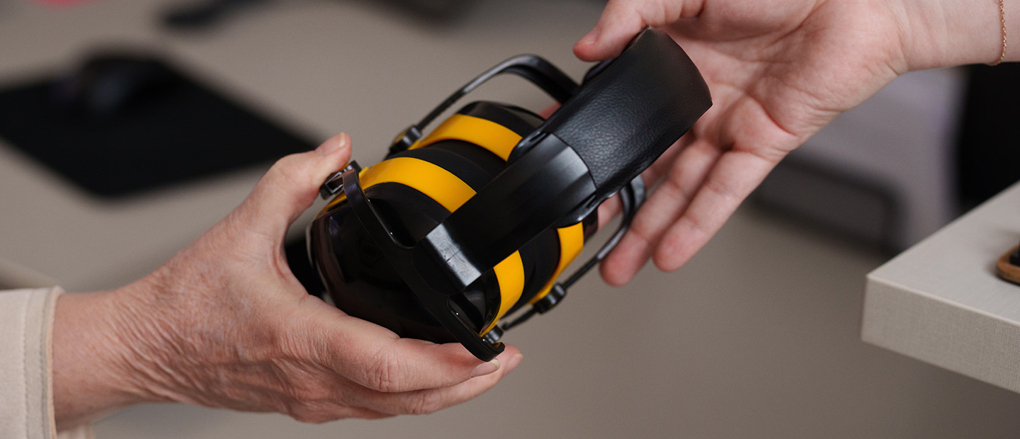 A person handing headphones to another person.