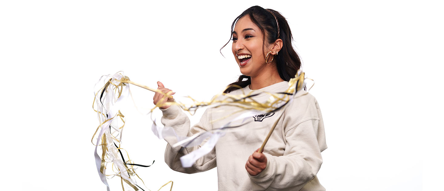 Young woman with long dark hair holding ribbon wands and smiling.