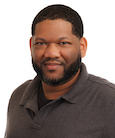 An African-American man with short black hair and a beard looking at the camera.