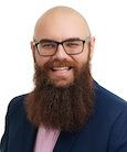 A bald man wearing glasses with a beard smiling and looking at the camera.