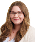 A woman with long brown hair and glasses smiling and looking at the camera.