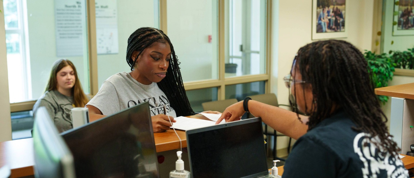 A student filling out a job application at a counter
