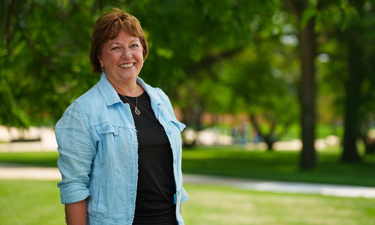 Beth Talbert stands smiling outside on O U campus.