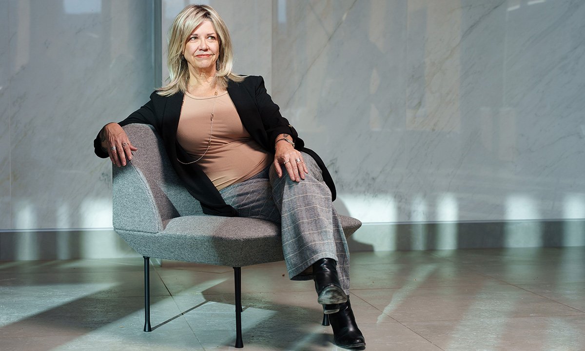 A woman sitting in a chair faces the camera.