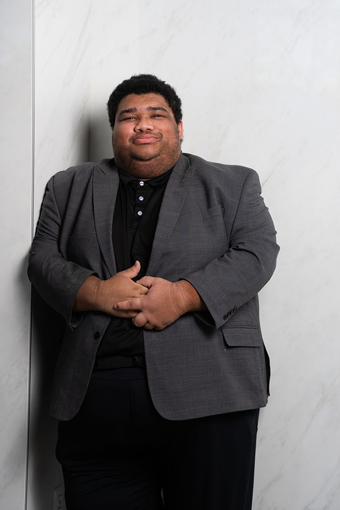 Marcus Johnson poses for a photo wearing a suit jacket and black shirt.