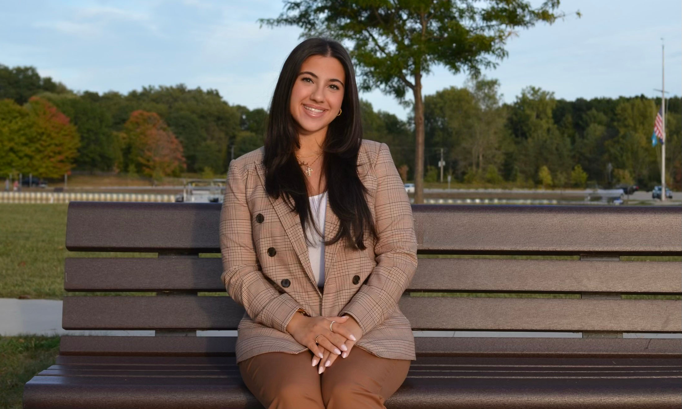 Oakland Political Science student Maria Williams sits on a bench outdoors.