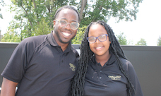 Two people wearing Oakland University polo shirts smiling.
