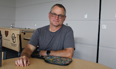 A smiling man sits at a desk.