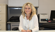 A smiling woman sits at a desk.