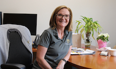 A smiling woman sits at a desk.