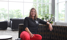 A smiling woman sits on a couch in a building on the O U campus.