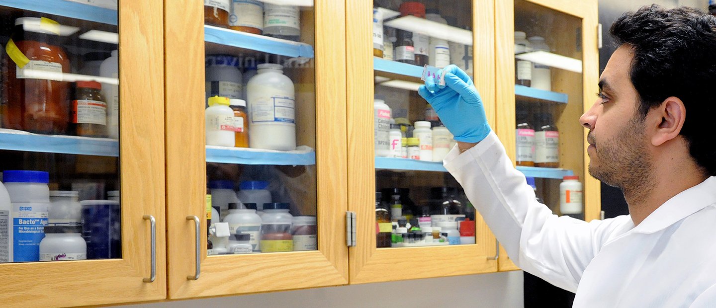 A man holding a microscope slide in a lab