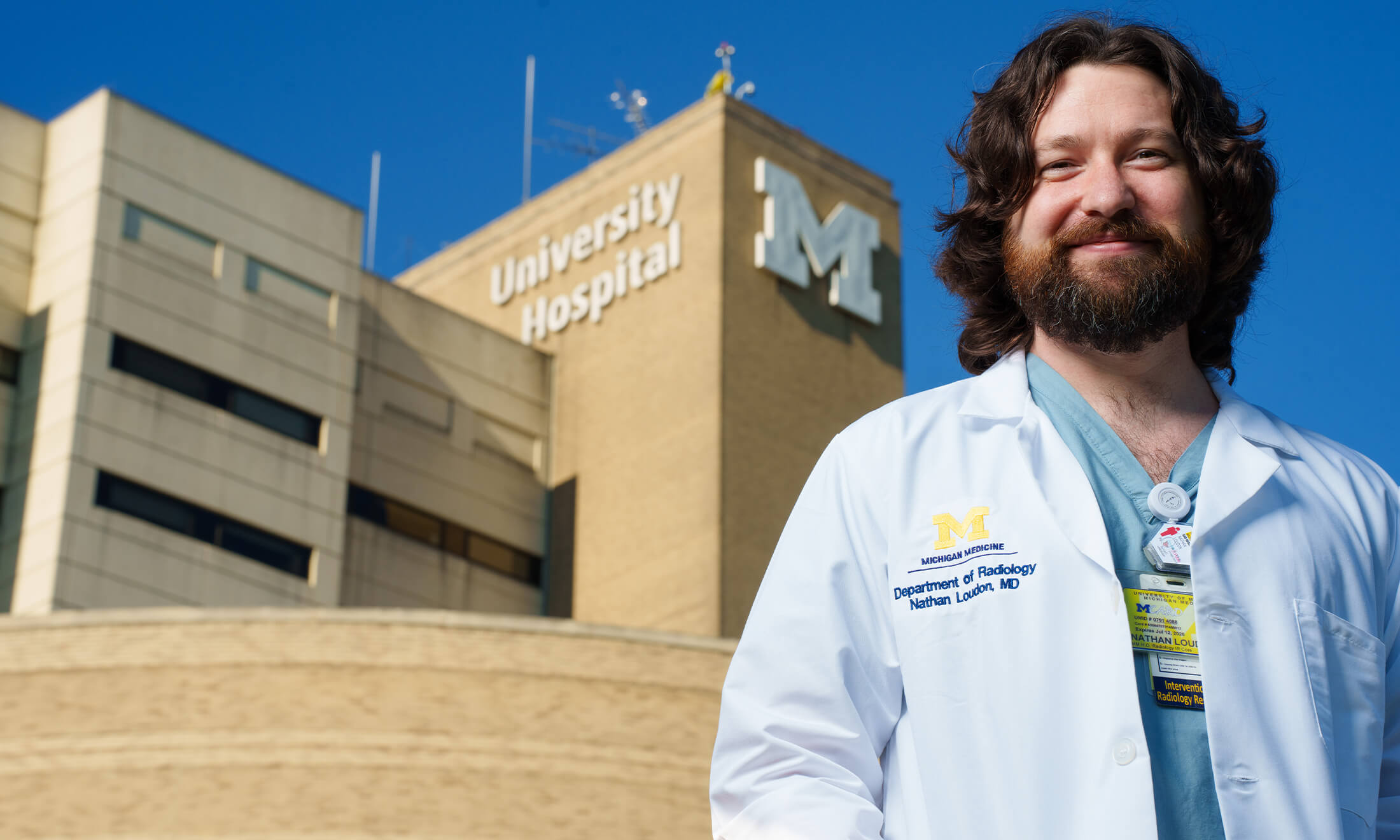 Man in medical coat smiling outside.