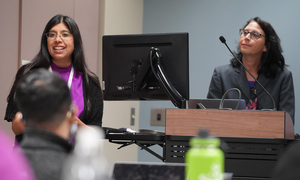 Two people speaking in front of a room