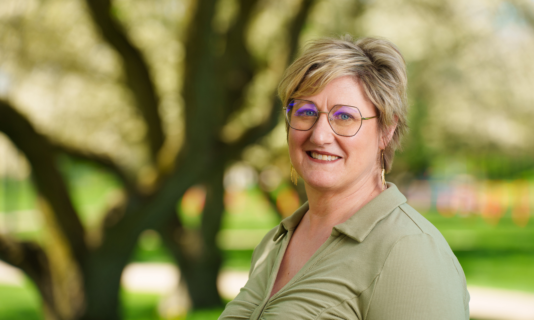 womand with glasses standing and smiling at camera