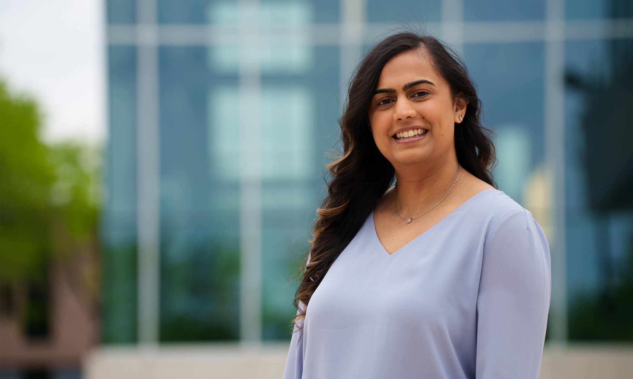 A woman stands outside a building smiling.