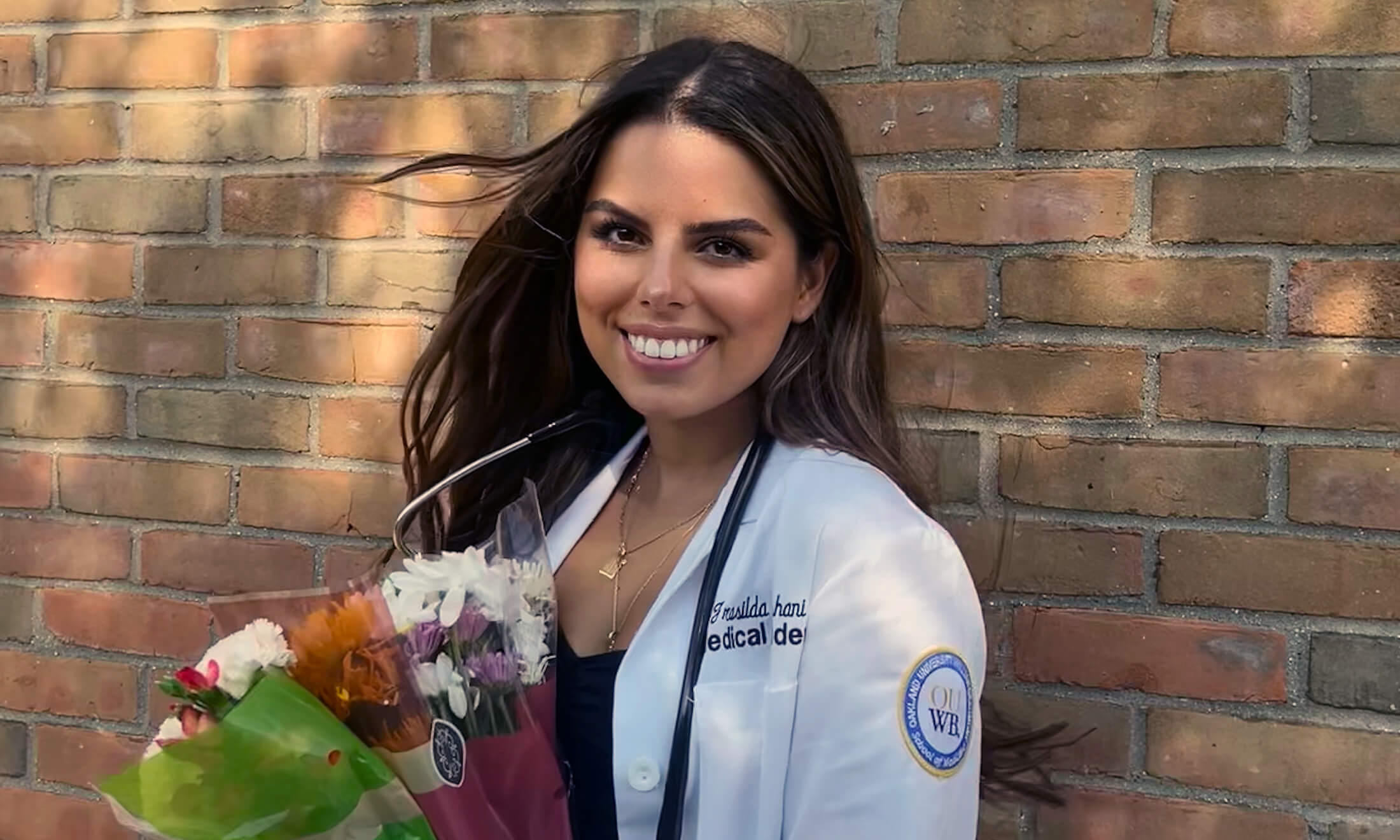 Woman in medical coat smiles at the camera