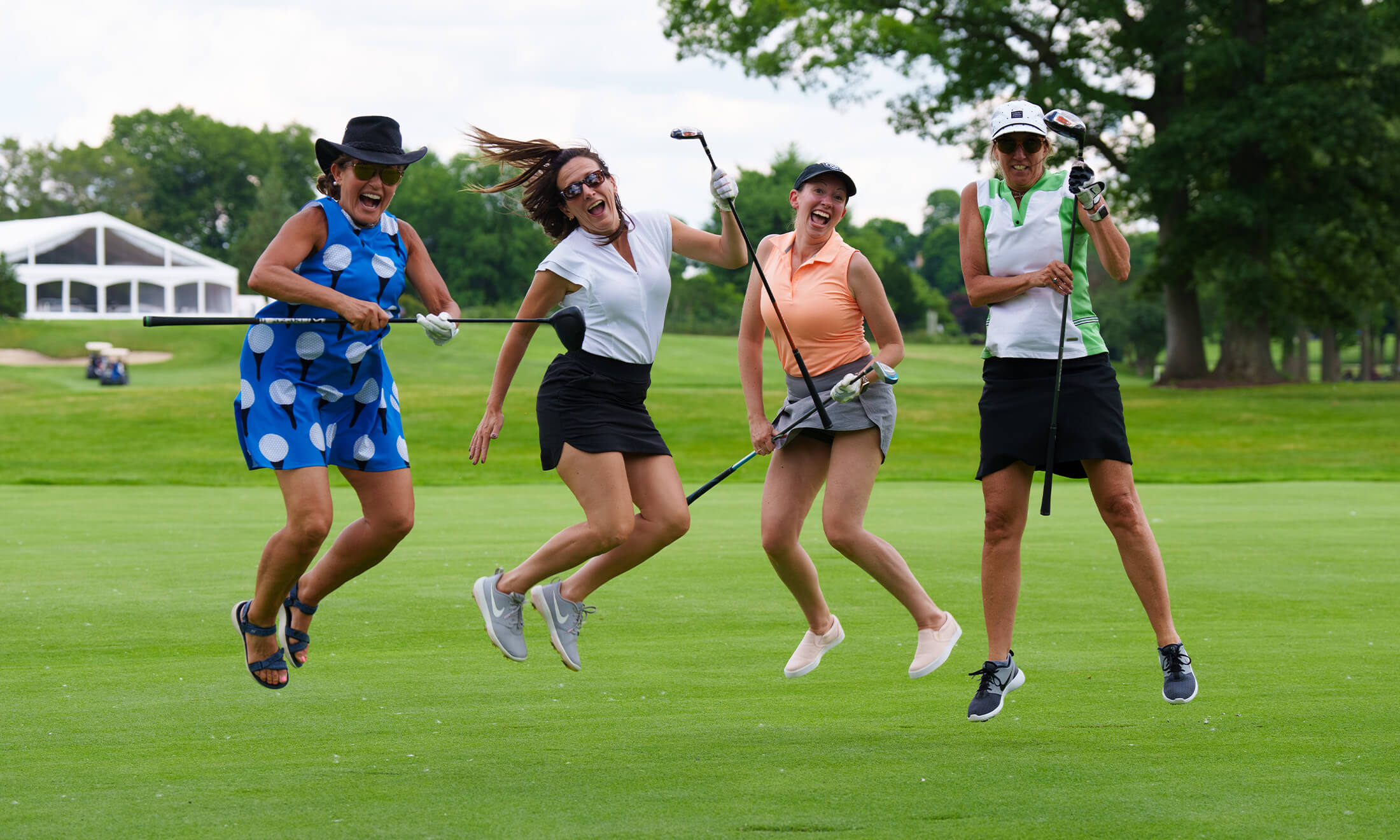 A group of golfers jumping smile a the camera.