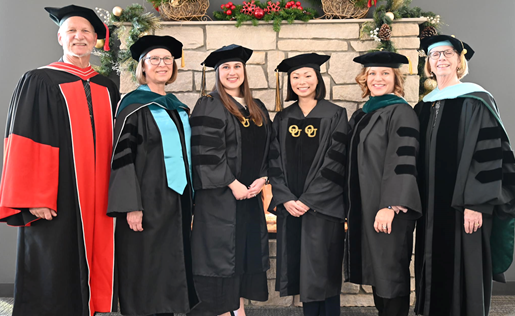 Group of 6 people standing side by side in graduation gowns