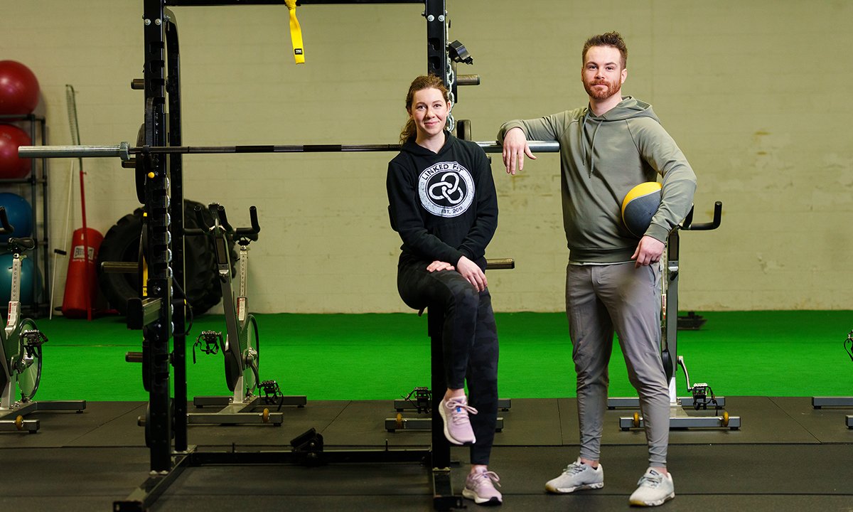 Man and woman in gym face the camera.