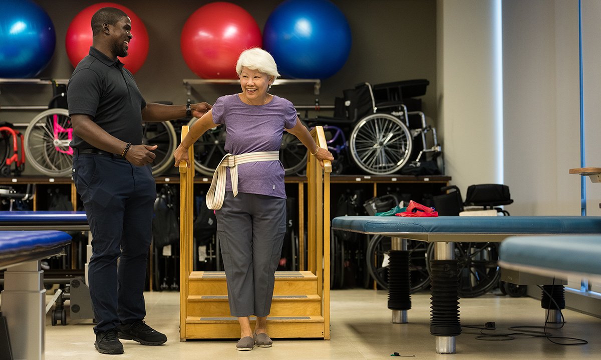 One person helping another person up stairs in a gym