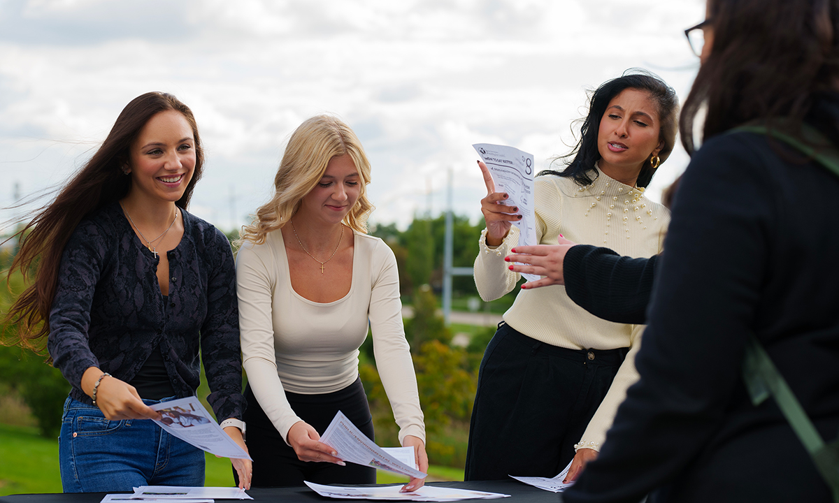 Three people at an outside table hand out flyers.