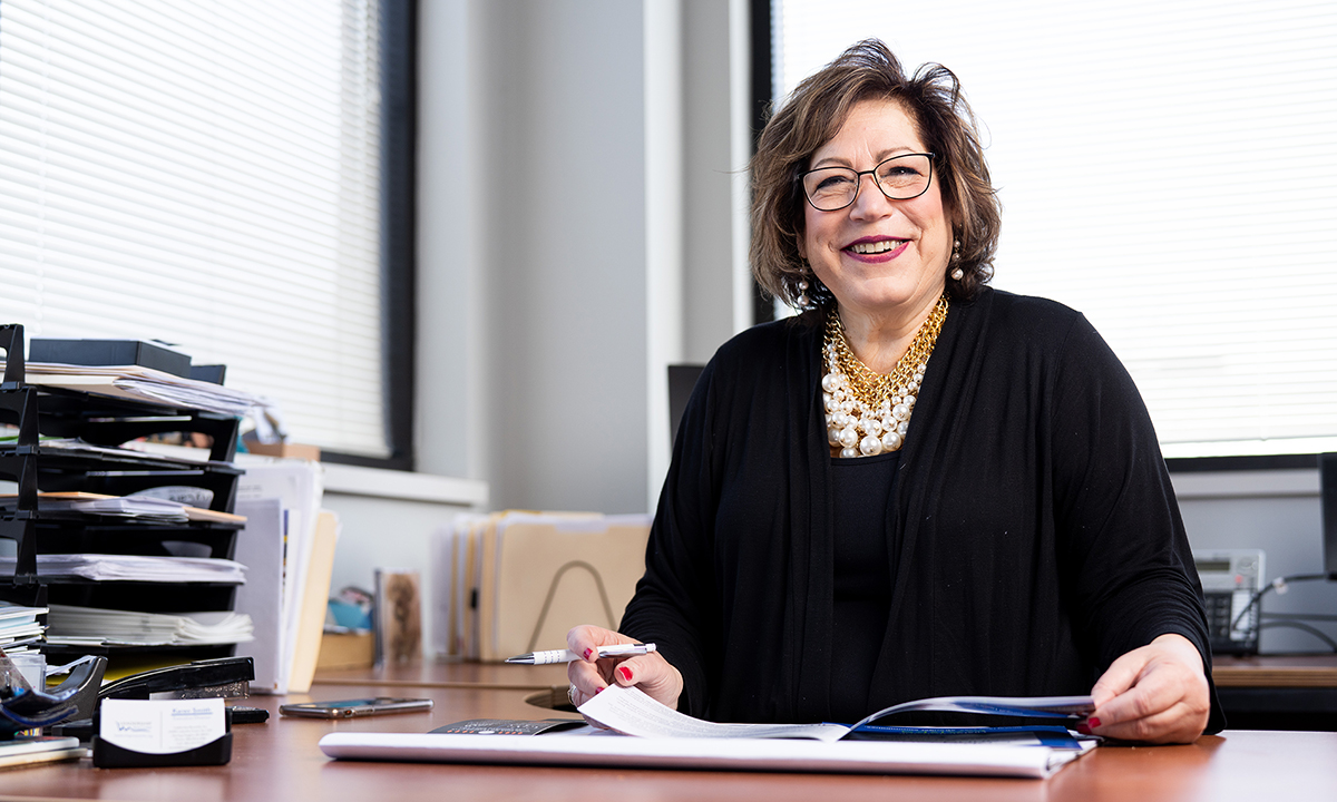 A woman smiling at her desk.