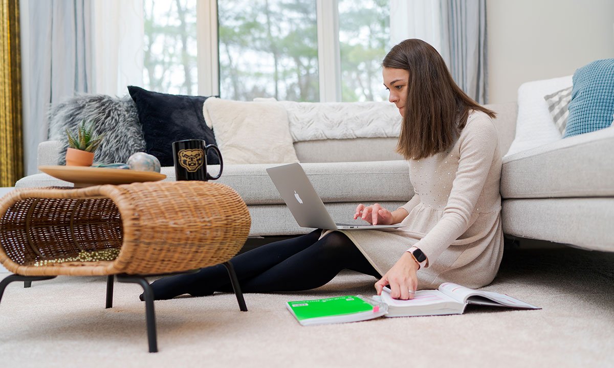 A woman sitting on the floor with a computer on her lap.