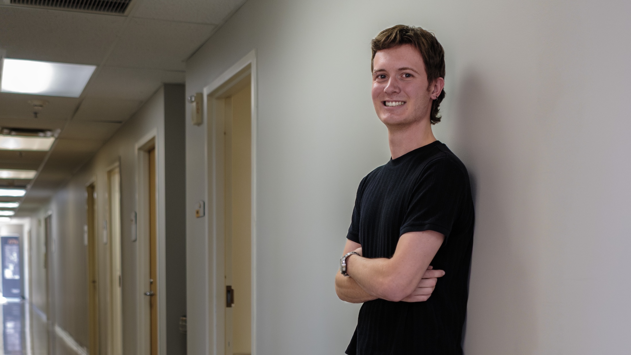student smiling leaning against wall