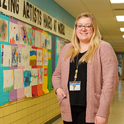 A female teacher standing in a hallway.