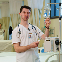 Man in nursing uniform faces the camera.