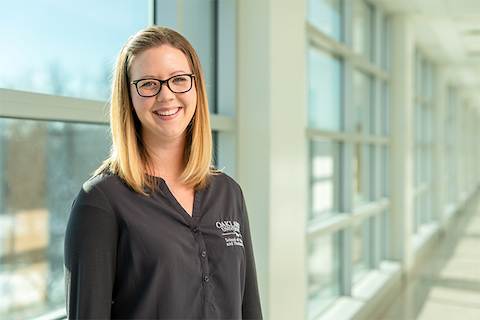 Woman smiling in front of windows.