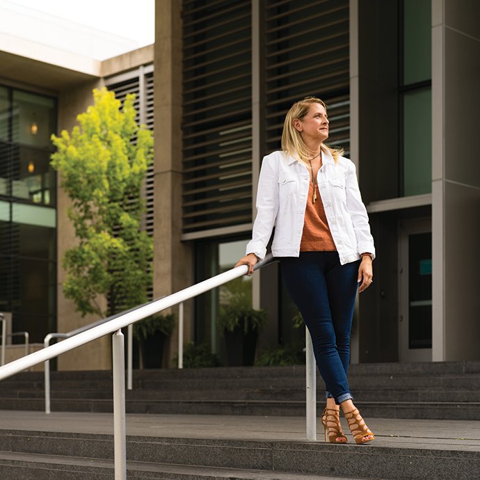 A woman leaning on a hand rail outside of a building.