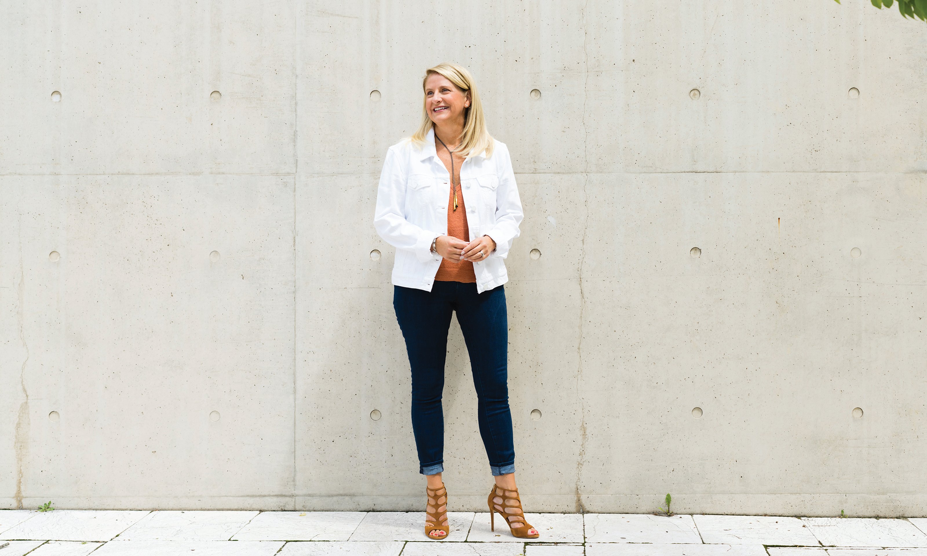 A woman standing in front of a concrete wall.